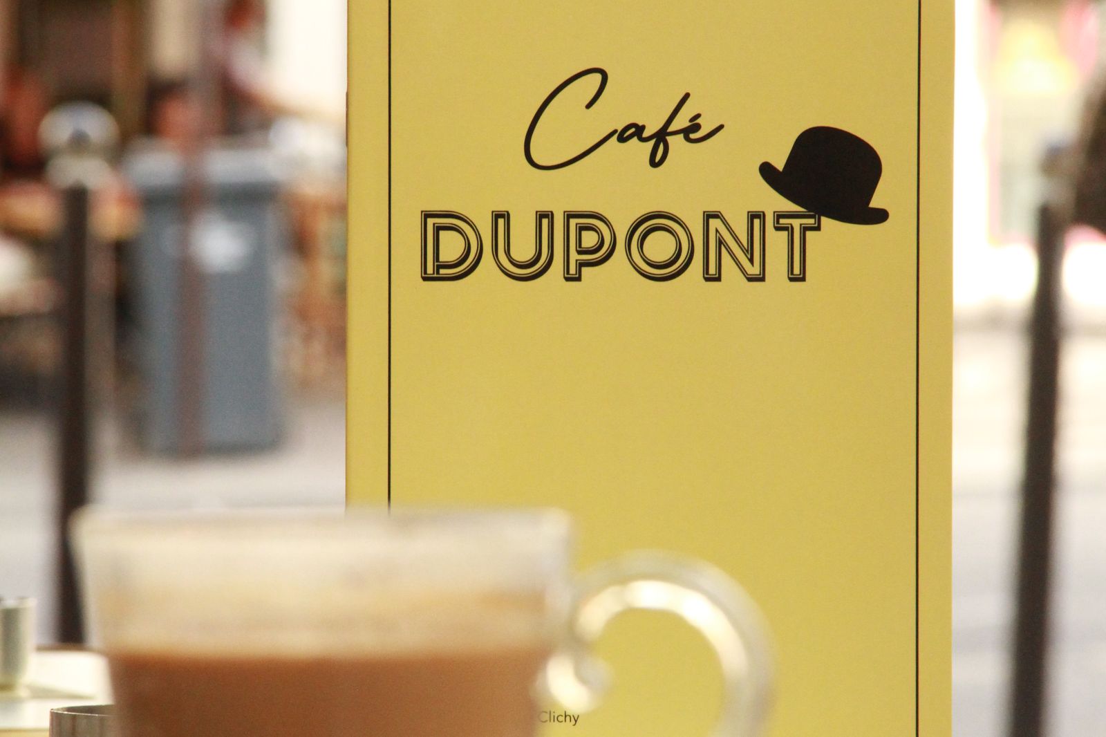 A coffee in front of the Café Dupont sign