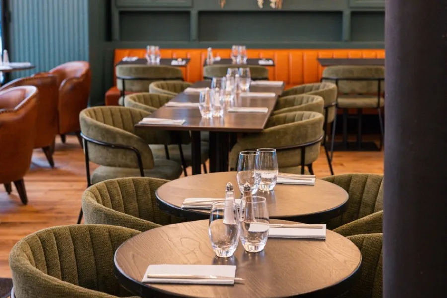 The dining room at Bistrot Jad, flowered cabinets and an orange banquette